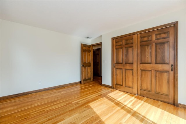 unfurnished bedroom featuring visible vents, a closet, light wood-style flooring, and baseboards