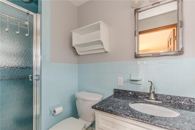 full bath with toilet, a wainscoted wall, vanity, tile walls, and a stall shower