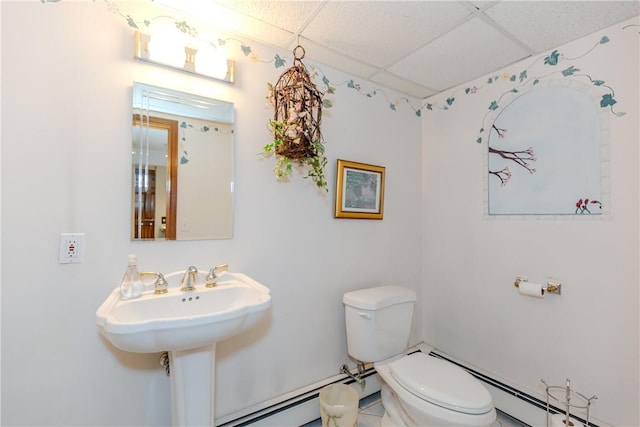 half bathroom featuring a baseboard heating unit, toilet, and a paneled ceiling