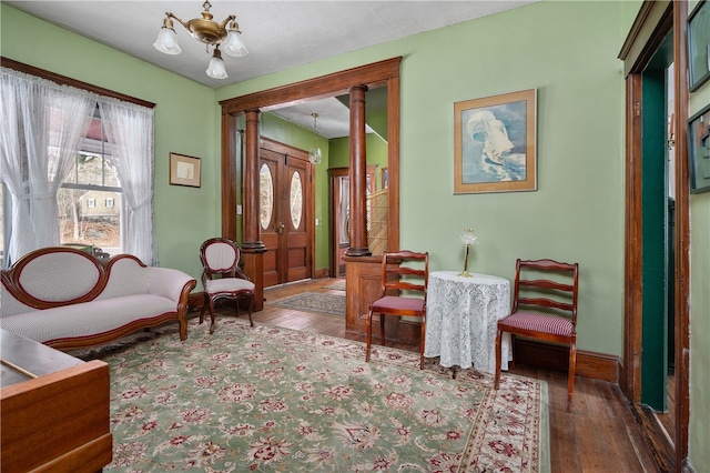 entrance foyer with a chandelier, hardwood / wood-style flooring, decorative columns, and baseboards