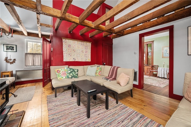 living area with beam ceiling, baseboards, and light wood finished floors