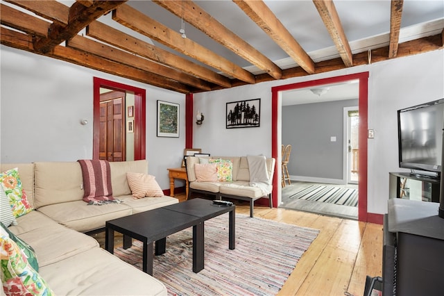 living area featuring light wood-type flooring, beam ceiling, and baseboards