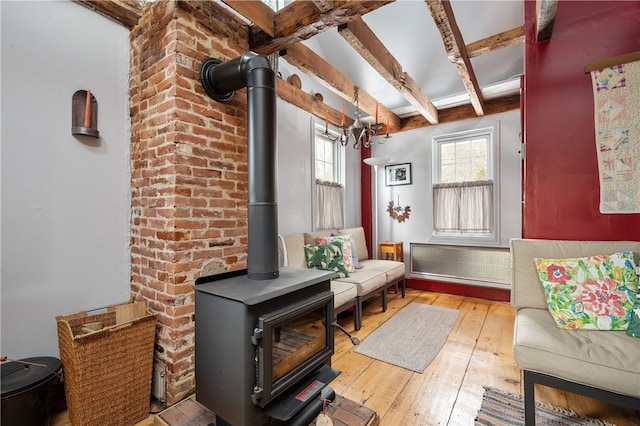 living area with a wood stove, hardwood / wood-style floors, and beamed ceiling