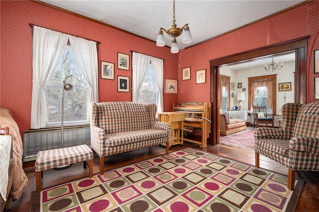 living area with wood-type flooring, a notable chandelier, and wallpapered walls