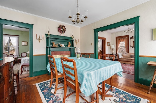 dining room featuring a chandelier, crown molding, wood-type flooring, and wallpapered walls