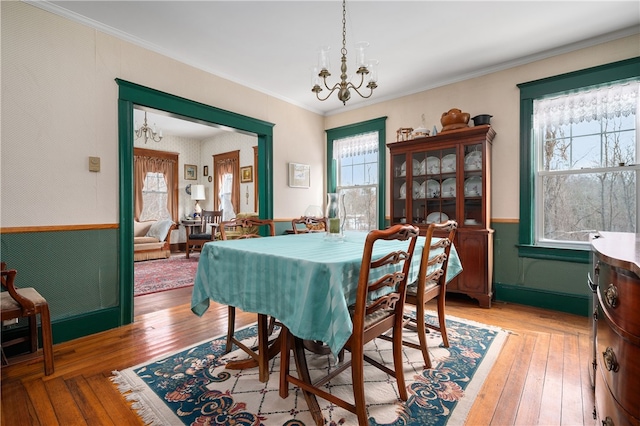 dining space featuring a healthy amount of sunlight, light wood-type flooring, and a notable chandelier