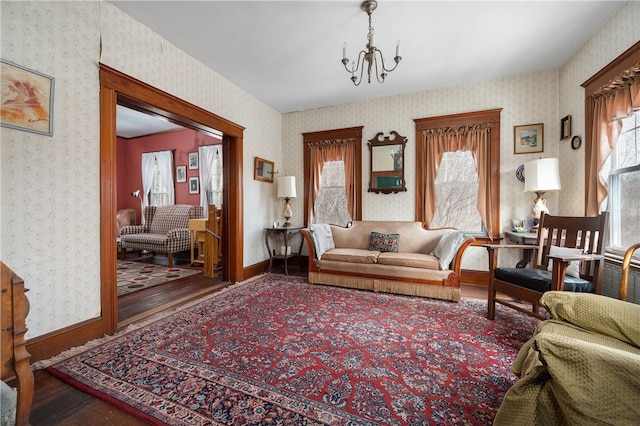 living area featuring wallpapered walls, baseboards, and wood finished floors