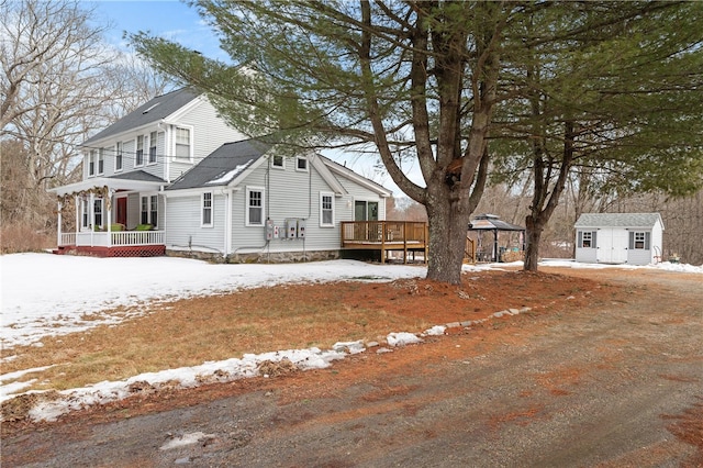 view of snowy exterior with a gazebo, an outbuilding, a porch, and a storage shed