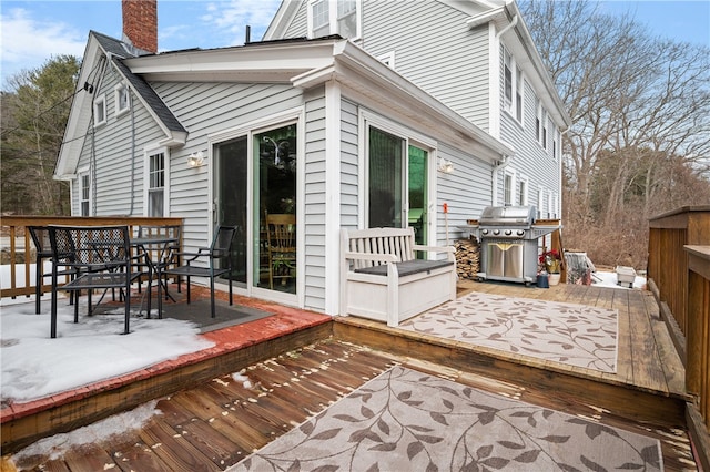 rear view of house with outdoor dining space, a chimney, and a wooden deck