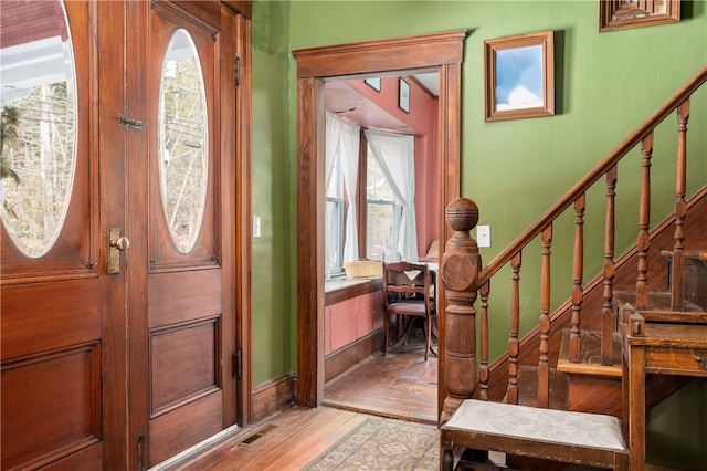 foyer with light wood-style floors, visible vents, stairs, and baseboards