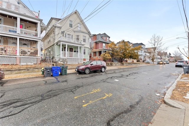 view of road featuring a residential view, curbs, sidewalks, and street lights