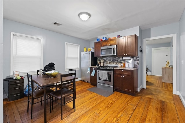 107 Lenox Ave, Providence, RI 02907 - kitchen featuring visible vents, light wood-style floors, light countertops, appliances with stainless steel finishes, and decorative backsplash