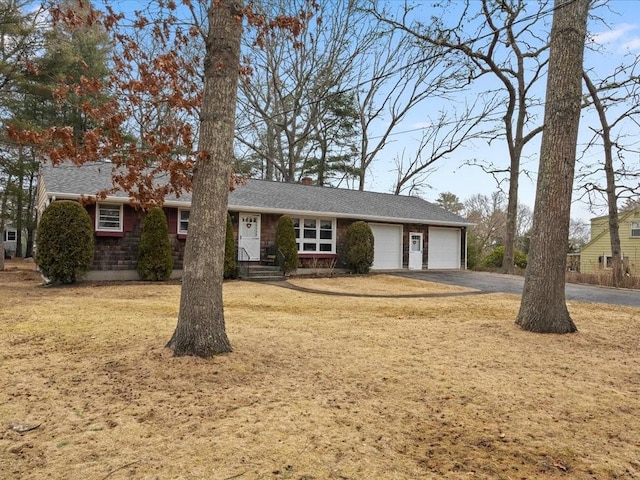 single story home with driveway, roof with shingles, and an attached garage