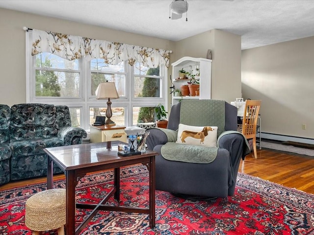 sitting room featuring a baseboard radiator, arched walkways, and wood finished floors