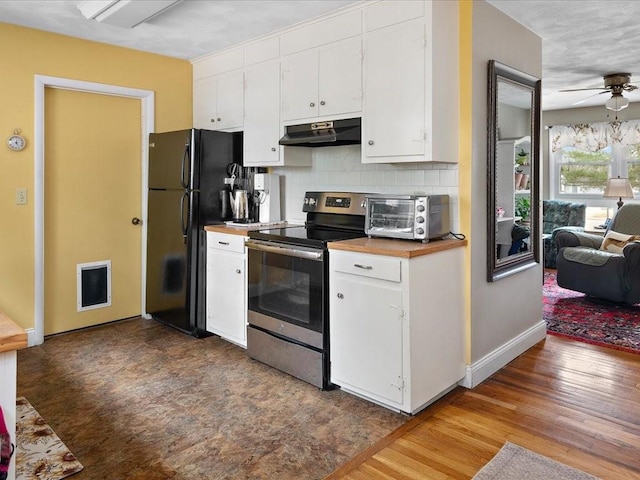 kitchen with a toaster, white cabinets, freestanding refrigerator, under cabinet range hood, and stainless steel range with electric stovetop