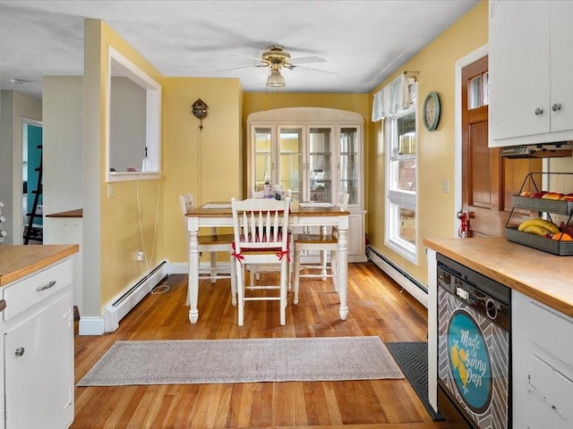 dining space featuring light wood finished floors, baseboards, and a baseboard heating unit