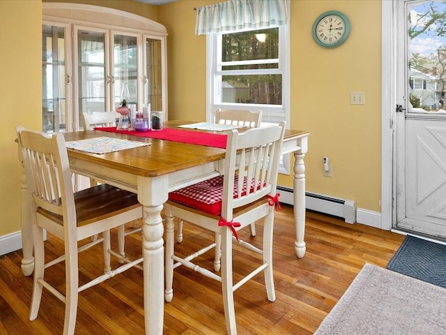 dining space featuring light wood-type flooring, baseboards, and a baseboard radiator