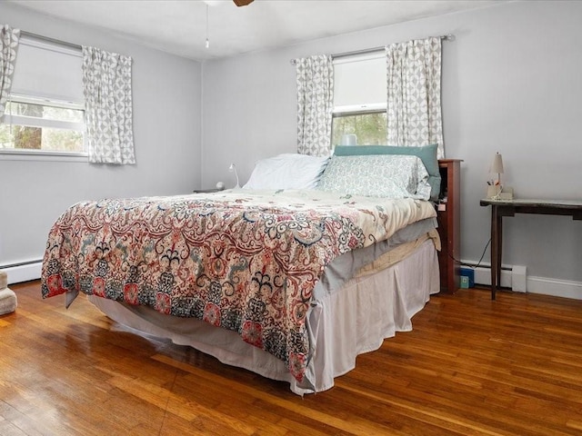 bedroom featuring a ceiling fan, a baseboard radiator, baseboards, and wood finished floors