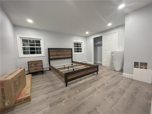 bedroom featuring recessed lighting, a closet, a baseboard radiator, wood finished floors, and baseboards