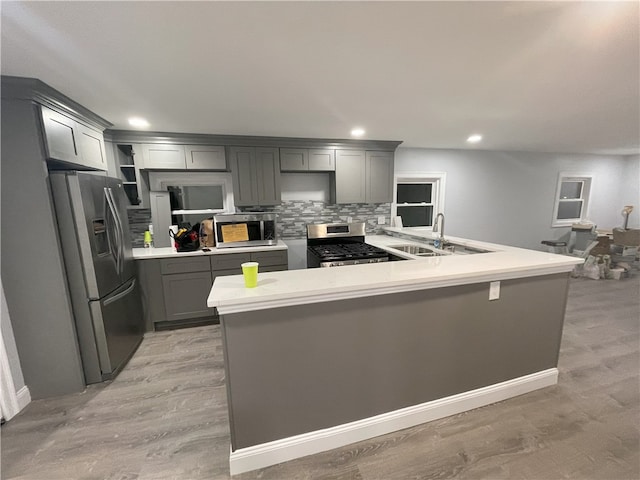 kitchen featuring appliances with stainless steel finishes, gray cabinets, light countertops, open shelves, and a sink