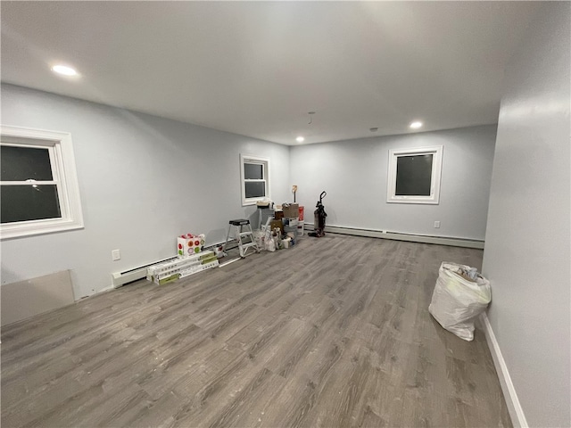 interior space featuring a baseboard radiator, baseboards, wood finished floors, and recessed lighting