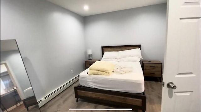 bedroom featuring a baseboard heating unit and wood finished floors