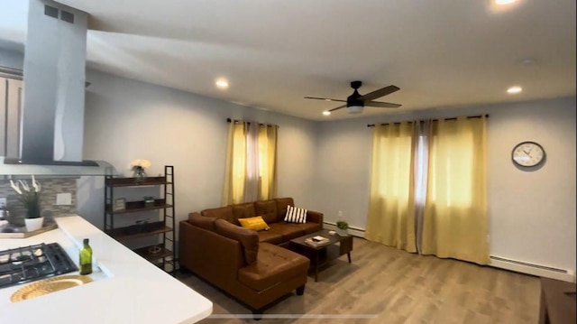 living area with a baseboard radiator, ceiling fan, light wood-style flooring, and recessed lighting