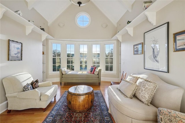 living area with high vaulted ceiling, wood finished floors, and baseboards