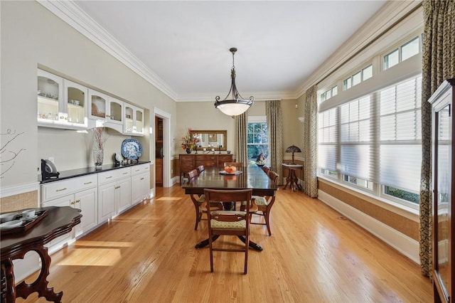 dining space featuring light wood-style floors, baseboards, and crown molding