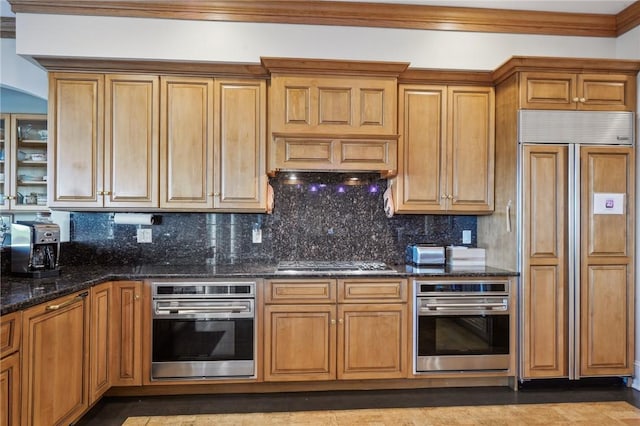 kitchen with backsplash, dark stone counters, stainless steel appliances, and crown molding