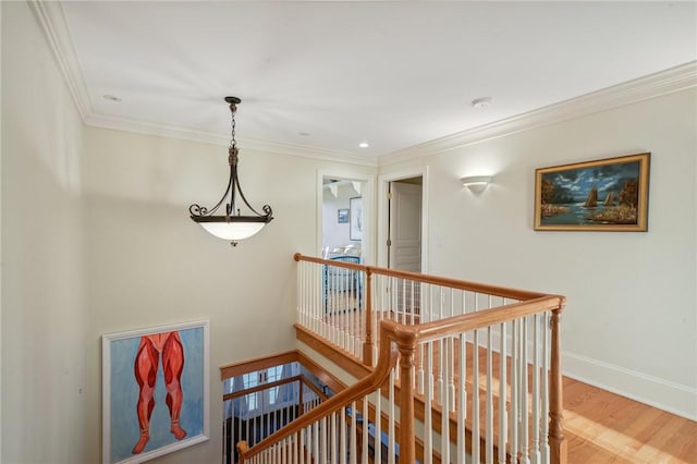 corridor featuring crown molding, baseboards, wood finished floors, and an upstairs landing