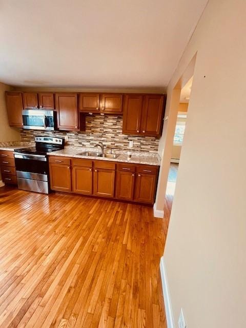 kitchen with light wood-style floors, stainless steel appliances, a sink, and light countertops