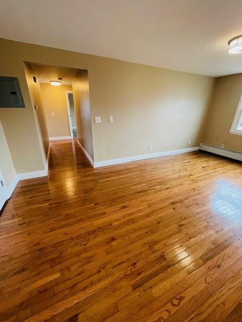 unfurnished room with a baseboard heating unit, wood-type flooring, electric panel, and baseboards