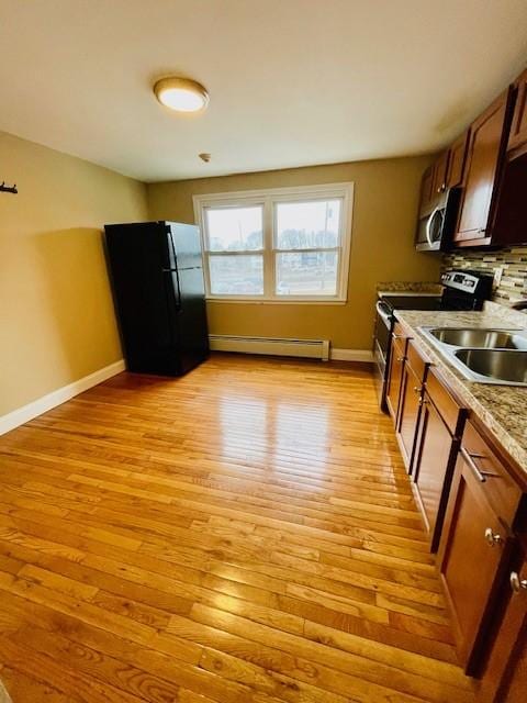 kitchen with a baseboard heating unit, appliances with stainless steel finishes, light wood-style flooring, and baseboards