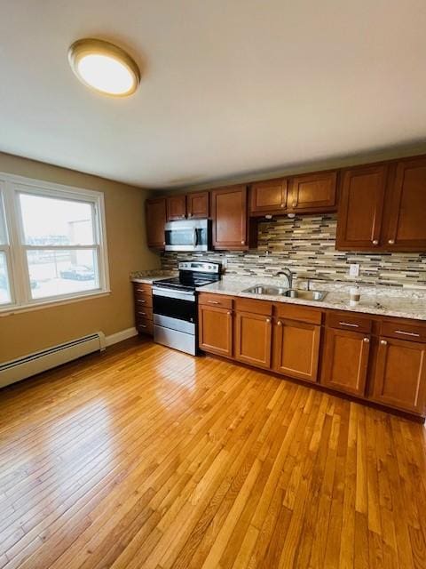 kitchen with backsplash, light wood-style flooring, stainless steel appliances, and a sink