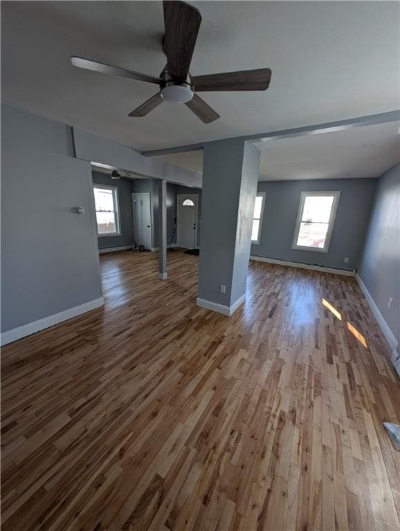 unfurnished living room with ceiling fan, baseboards, and wood finished floors