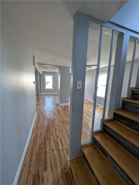 hall with wood finished floors, baseboards, and stairs