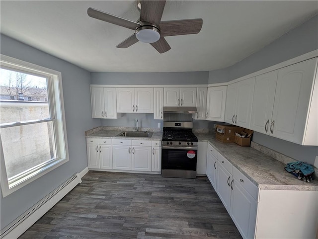 kitchen featuring a baseboard heating unit, under cabinet range hood, white cabinetry, a sink, and gas stove