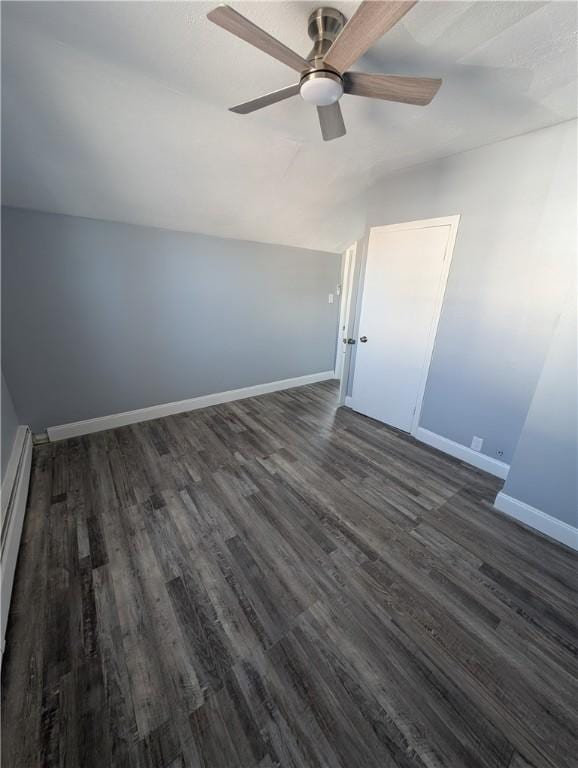 interior space featuring lofted ceiling, a baseboard heating unit, a ceiling fan, baseboards, and dark wood finished floors