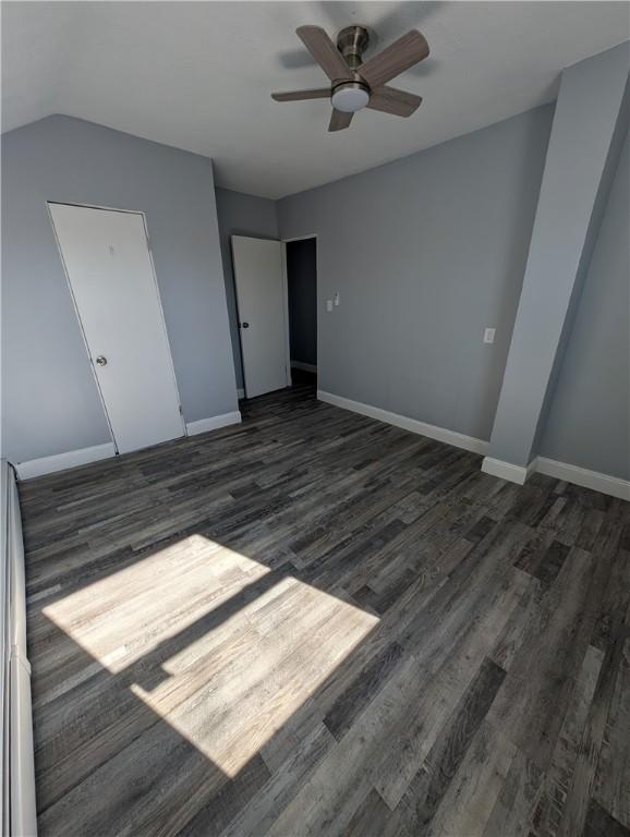 unfurnished bedroom with a ceiling fan, lofted ceiling, baseboards, and wood finished floors