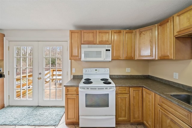 kitchen with dark countertops, white appliances, light tile patterned flooring, and french doors