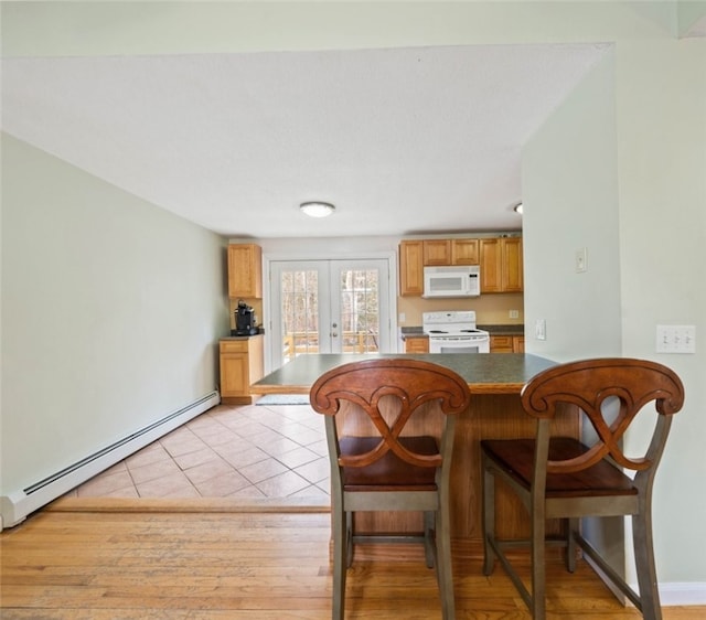 kitchen with a peninsula, white appliances, french doors, baseboard heating, and dark countertops