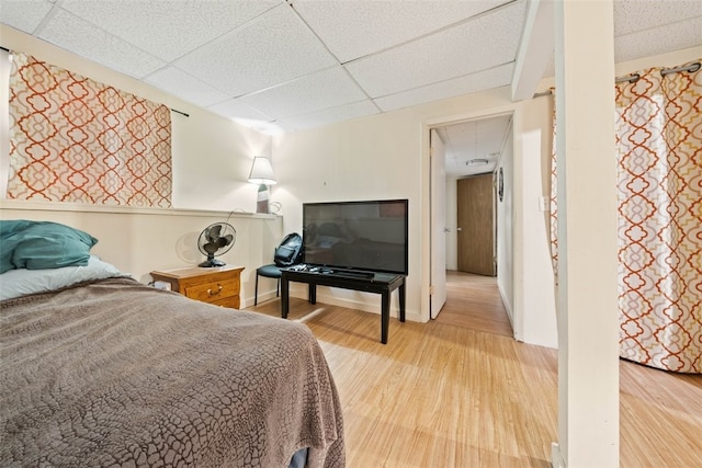 bedroom with light wood-type flooring and a drop ceiling