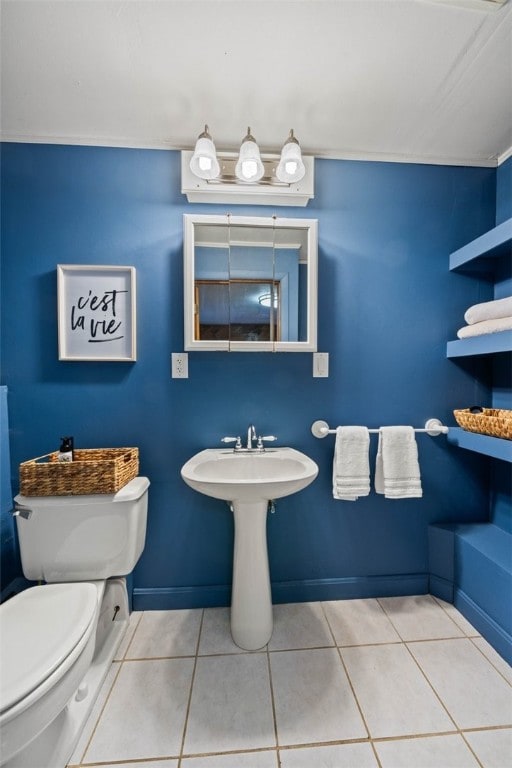 bathroom featuring toilet, baseboards, a sink, and tile patterned floors