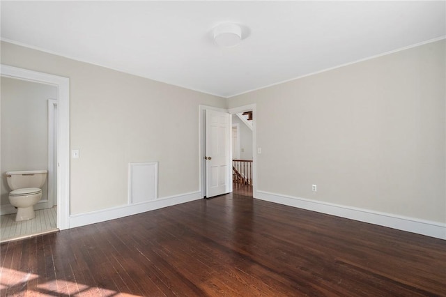 unfurnished bedroom with ensuite bath, baseboards, and wood finished floors