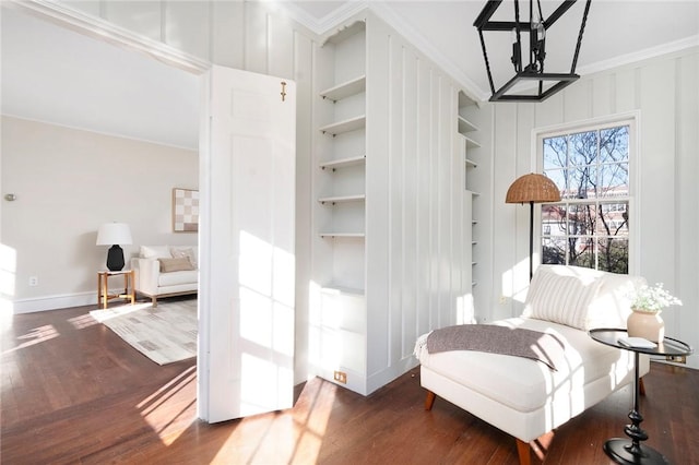 sitting room featuring baseboards, built in features, crown molding, and wood finished floors