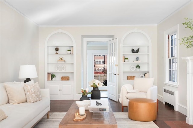 sitting room featuring built in shelves, radiator, plenty of natural light, and ornamental molding