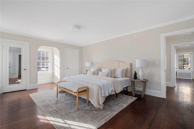 bedroom featuring radiator, baseboards, arched walkways, and wood finished floors