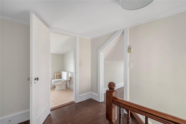 hallway featuring crown molding, dark wood finished floors, radiator, an upstairs landing, and baseboards