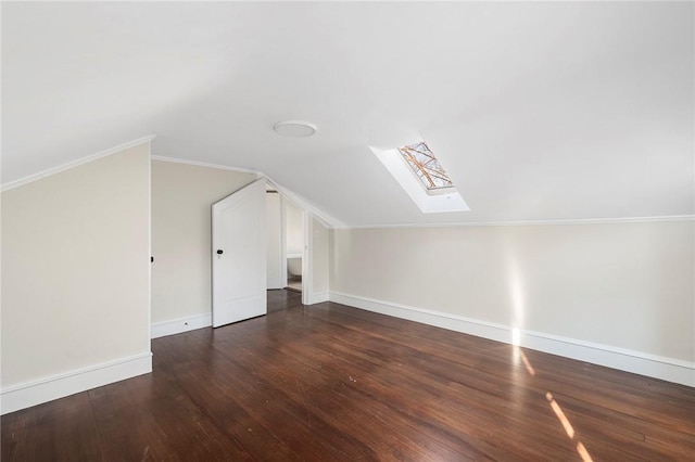 additional living space with lofted ceiling with skylight, wood finished floors, and baseboards